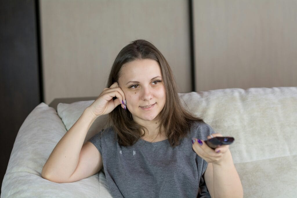 Woman turning up the TV volume, early sign of age-related hearing changes, natural hearing support supplement concept