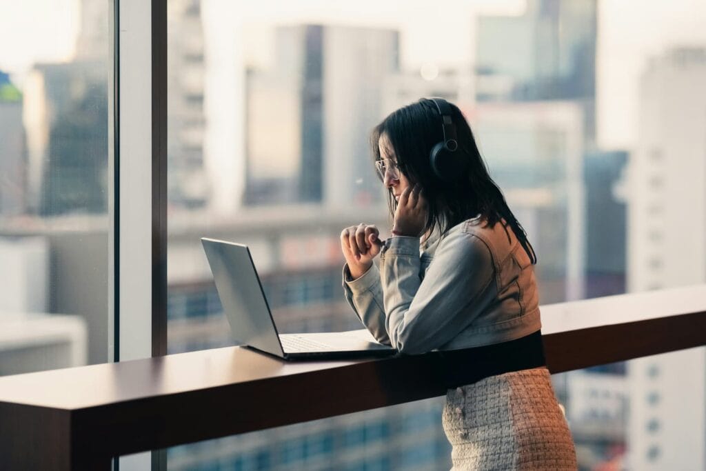Woman looking away from her computer screen toward a window, practicing the 20-20-20 rule to reduce eye strain
