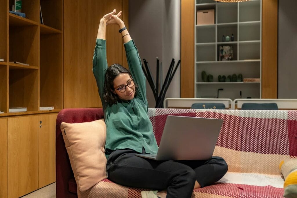 Woman stretching her hands and wrists at her desk, healthy habit to support nerve health