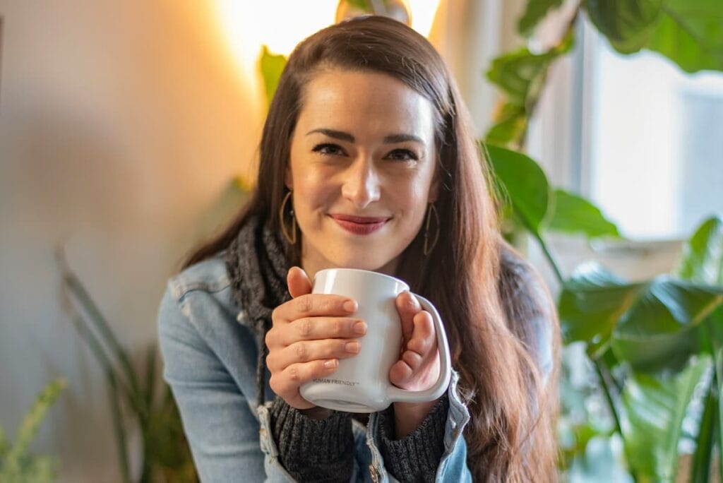 Woman warming her cold hands with a mug of tea, sign of poor circulation, natural nitric oxide circulation support supplement concept