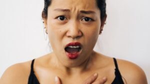 Woman with a surprised expression holding her hand to her chest